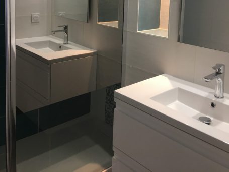 Salle de bain moderne avec deux lavabos, miroirs et meuble sous vasque.