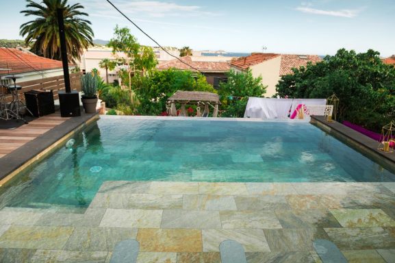 Piscine à débordement avec vue sur la mer et végétation environnante.