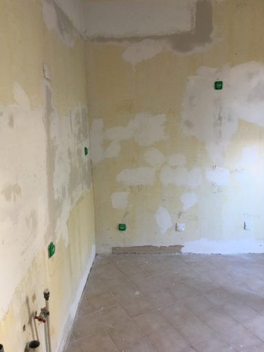 Chambre avec murs décolorés et des zones non peintes, sol carrelé.