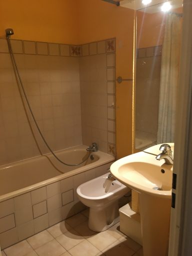 Salle de bain avec baignoire, bidet, lavabo et murs jaunes.