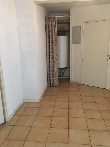 Intérieur d'une pièce avec un mur de plâtre, un rideau et un chauffe-eau visible.