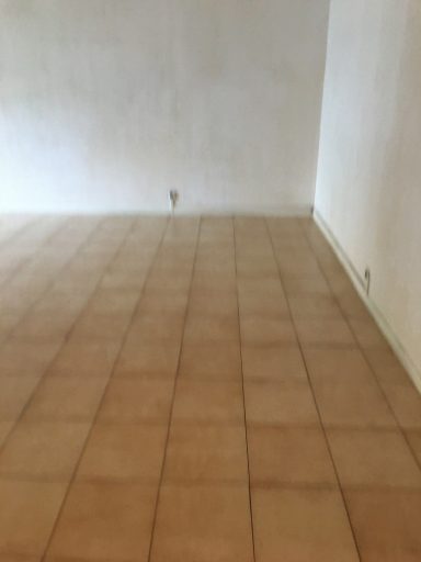 Sol en carrelage beige dans une pièce avec des murs clairs.